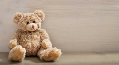 Oyuncak ayı boş bir tahta zeminde oturuyor. Tahta masadaki kahverengi, üzgün, tüylü hayvan oyuncağı. Doğum günü, sevgililer günü, Noel hediyesi. Boşluğu kopyala
