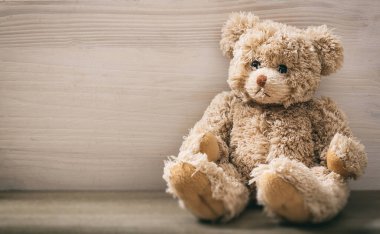 Oyuncak ayı boş bir tahta zeminde oturuyor. Tahta masadaki kahverengi, üzgün, tüylü hayvan oyuncağı. Doğum günü, sevgililer günü, Noel hediyesi. Boşluğu kopyala