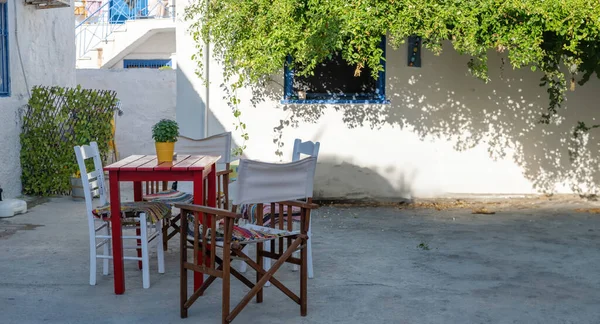 伝統的な木製の椅子とテーブルの上のバジル 植物が付いている白く洗われた建物の庭が付いている鍋 ギリシャ メガロチョーリ ミロス ミロイ港 アグスタ島 — ストック写真