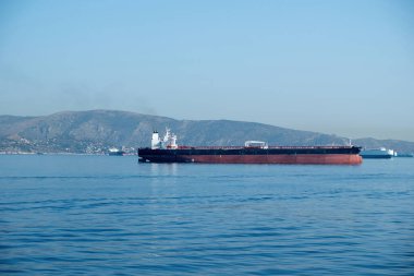 Konteynır kargo gemisi Yunanistan 'ın Pire limanındaki Akdeniz' de yüklendi. İthalat işi ve lojistik. Sakin su, mavi gökyüzü arka planı.