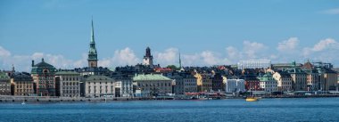 Gamla Stan, Stockholm 'de Old Town' un panoramik manzarası. Geleneksel rıhtım renkli bina, limanda demirli tekne, mavi gökyüzü arka planı. Pankart