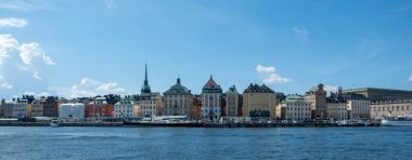 Stockholm İsveç. Gamla Stan, Eski Şehir 'in panoramik manzarası, geleneksel rıhtım binaları, limanda demirli tekne, mavi gökyüzü arka planı.. 