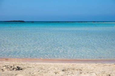 Yunanistan, Girit 'teki Elafonisi' deki kumsal. Pembe kum, şeffaf sakin deniz suyu, berrak mavi gökyüzü arkaplanı. Yaz tatili için.