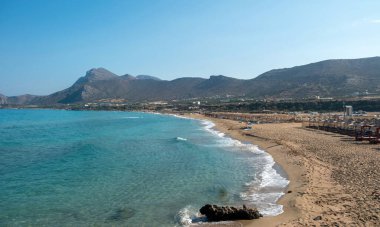 Girit Adası Yunanistan 'daki Falasarna kumlu plajı. Şemsiye, deniz yatağı, yaz tatili, doğa, dalgalı deniz, mavi gökyüzü, güneşli bir gün..