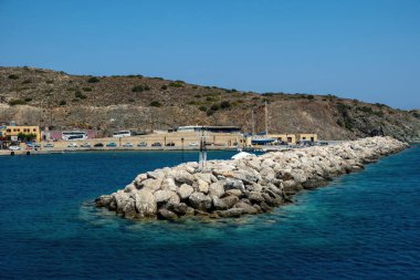 Yunanistan, Gavdos adası, Girit tatil beldesi. Liman, dalgalı deniz suyu, kayalık dalgalar üzerindeki fener, bina, yaz güneşli bir gün..