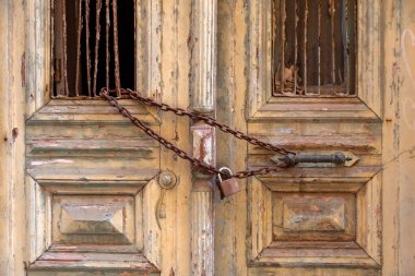 Paslı zincir ve asma kilit kırık pencereli tahtadan bir girişte. Karmaşık yıpranmış kapısı olan terk edilmiş bir Yunan evi..