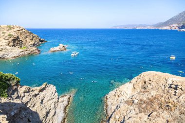 Yunanistan adası yaz mevsimi. Uçsuz bucaksız Ege Denizi 'nde demirli bir tekne, yaz güneşli bir gün. İnsanlar turkuaz su arka planında yüzer. Görünümün üstünde