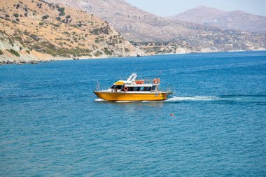 Yunanistan adası yaz mevsimi. Ege 'nin deniz suyu arka planında sarı yolcu gemisi, yaz güneşli bir gün. Yüzmek, dinlenmek, güneşlenmek..