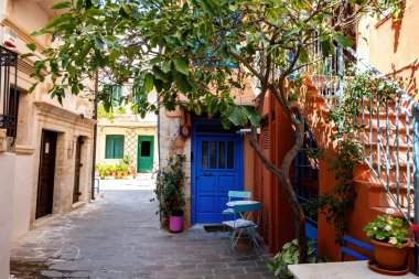 Chania Old Town, Girit adası Yunanistan. Geleneksel bina, masa, iki sandalye ve tencere bitkisi dar, boş asfalt avluda, yaz güneşli bir günde.