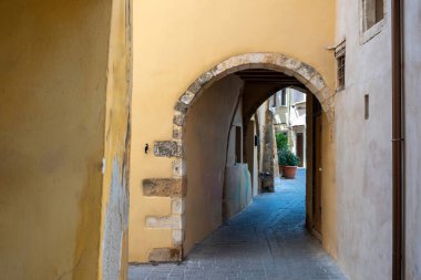 Chania Old Town, Girit adası, varış noktası Yunanistan. Kemerli taş duvar dar, boş asfalt yolu kapatıyor. Yaz tatili, güneşli gün, keşif.