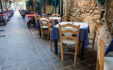 Girit adası Yunanistan 'daki Chania Old Town' da geleneksel meyhane. Boş sandalye masası, saksı çiçeği, asfalt sokak, yaz günü..
