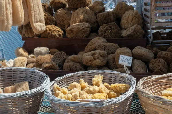 Natural sea sponge for sale with price label at outdoors shop bench in Greece. Pile of whole or piece dry organic sponge. Bath, spa, healthcare.