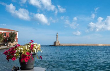 Yunanistan, Eski Chania Girit Kasabası. Deniz feneri manzarası, açık kafeden Venedik limanındaki deniz feneri. Pembe tencereli masa, beyaz petunya..