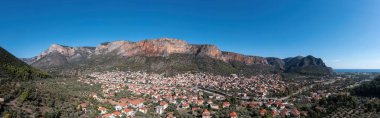 Yunanistan, Leonidio, Arcadia, Moreloponnese. Geleneksel bina, dağ, uçurum, deniz suyu, mavi gökyüzü ile şehrin panoramik hava aracı görüntüsü. Pankart