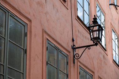 Açık hava antika fener armatürü bina arka planının kahverengi duvarına monte edildi. Eski model metal ve cam lamba direği ışığı. Görüntü altında.