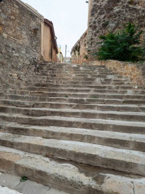 Yunanistan 'ın başkenti Chania Girit' teki geleneksel taş duvar binası arasındaki eski yıpranmış taş merdiven. Mavi gökyüzü arka planı. Dikey