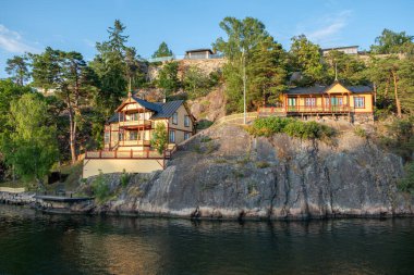 Traditional luxury villa at seaside of Sandhamn, Archipelago, Stockholm Sweden. Reflection of cottage in sea water, view of nature from cruise boat. clipart