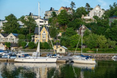 Stockholm, İsveç. Rıhtım manzaralı villa, Archipelago 'daki kır evi. Deniz suyunda yansıma, limanda demirli tekne, mavi gökyüzü arka planı..