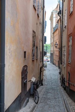 İsveç, geleneksel renkli bina, dar, dolambaçlı kaldırım yolu Stockholm 'de park edilmiş bisiklet, varış yeri Gamla Stan Old Town. Dikey