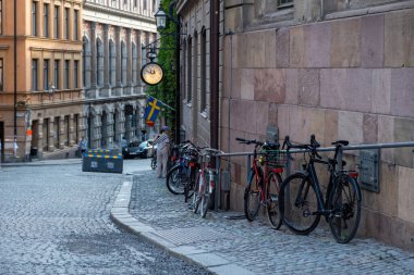 Geleneksel renkli bina, dolambaçlı kaldırım yolu Stockholm 'de park edilmiş ve kilitlenmiş bisiklet İsveç kültürü, varış yeri Gamla Stan Old Town.
