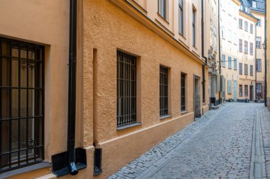 Stockholm İsveç. Gamla Stan Eski Kasabası 'nda harici lağım arka planına sahip vintage binalar arasındaki boş dar asfalt geçidi.