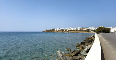 Tinos Adası, Cyclades 'in varış noktası Yunanistan. Beyazlatılmış bina, şeffaf dalgalı deniz, kumlu ve çakıllı plaj, mavi gökyüzü arka planı.