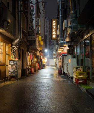 Hiroşima Japonya. Nisan 03, 2024. Kapalı dükkan, aydınlık dükkan ve yağmur yağan bir gecede sokak asfaltındaki ışığın yansıması arasındaki boş ıslak cadde. Dikey
