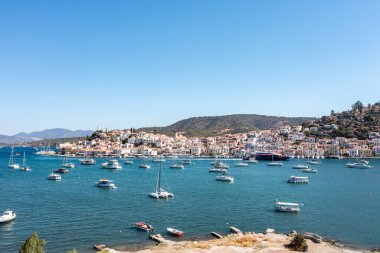 Greece, Aerial drone view of Poros island in  Saronic gulf, Peloponnese, Seafront buildings on the coast and boats in the sea, blue sky clipart