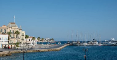 Spetses Adası, Yunanistan. Eski neoklasik binalar, gezinti güvertesi. Yatlar ve yelkenliler marinada demirli, mavi gökyüzü