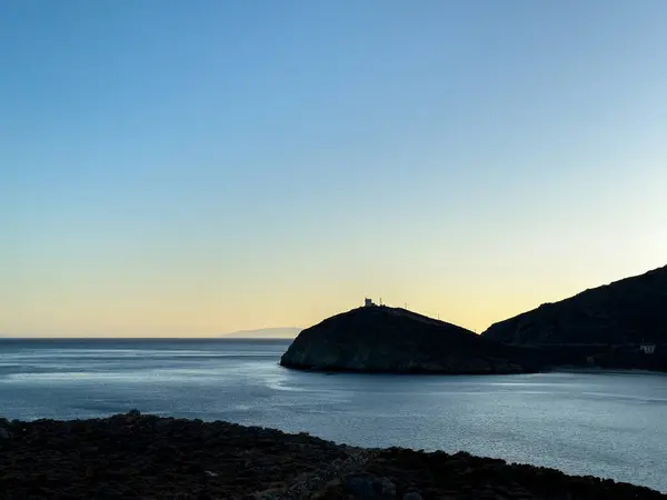 Stock image Greece, Seascape at Andros island Greece. Silhouette of a lighthouse on the hill at dusk