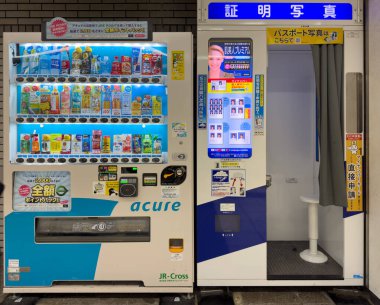 Tokyo Japonya. 11 Nisan 2024. İçecek ve içecek karşılığında otomat parası, kimlik fotoğraf kabininin yanında. Aydınlatılmış self servis sokak dükkânı.