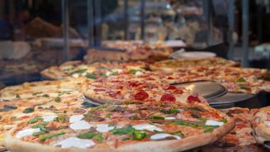 Pizzacı dükkânı. Pizzacı camından yapılmış çeşitli İtalyan pizzaları. Yakın çekim. NYC 'de sokak yemeği