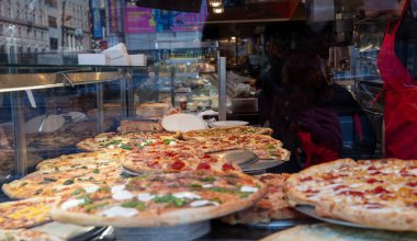 Pizzacı dükkânı. Pizzacı camından yapılmış çeşitli İtalyan pizzaları. Yakın çekim. NYC 'de sokak yemeği
