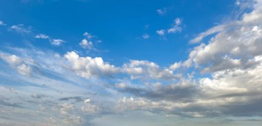 Mavi arka planda tüylü kümülüs bulutları. Bulutlar beyaz ve gri renkli. Hava ve meteoroloji