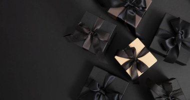 Kara Cuma indirimi konsepti. Siyah arka planda kurdele ile siyah hediye kutuları, üst görünüm