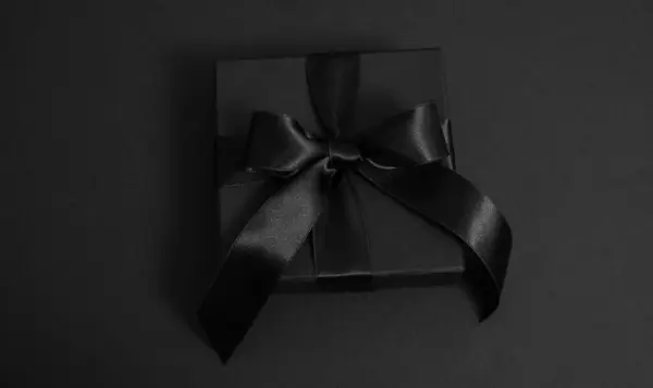 stock image Black Friday Sale. Black gift box with ribbon bow isolated on black, closeup top view