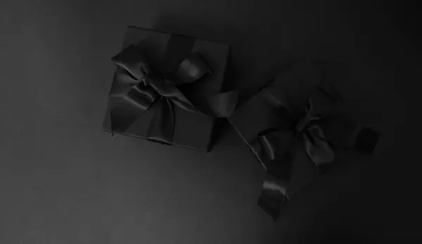 stock image Black Friday Sale. Black gift boxes with ribbon bow isolated on black, closeup top view