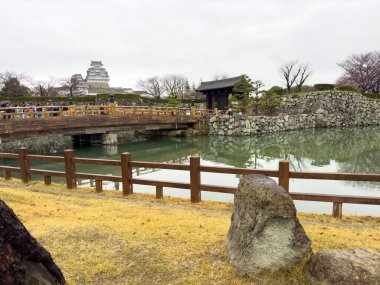 Himeji Japan. April 3, 2024. Sakuramon bridge at the Otemon entrance gate, white Heron castle main keep cloudy sky clipart