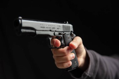 Silahlı ve yakın plan silahlı bir adam, karanlık arka planda tabanca tutan bir adam. Tehlike ve suç kavramı