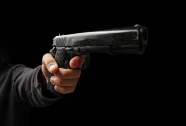 Silahlı ve yakın plan silahlı bir adam, karanlık arka planda tabanca tutan bir adam. Tehlike ve suç kavramı