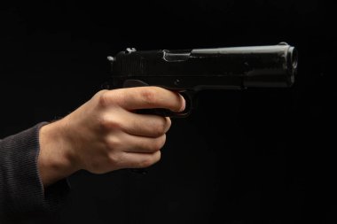 Silahlı ve yakın plan silahlı bir adam, karanlık arka planda tabanca tutan bir adam. Tehlike ve suç kavramı