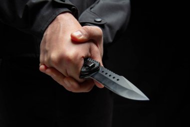İki eli de yakın bıçak tutan bir suçlu. Siyah arka plan, silahlı saldırı konsepti..