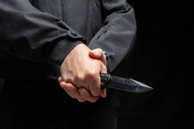 İki eli de yakın bıçak tutan bir suçlu. Siyah arka plan, silahlı saldırı konsepti..