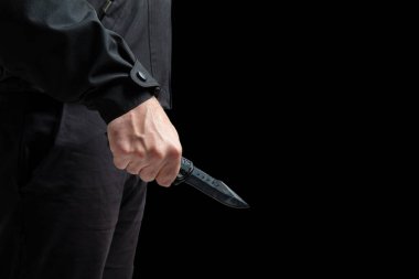 Suçlunun elinde bıçak var. Yakın plan, siyah arkaplan, silahlı saldırı konsepti..
