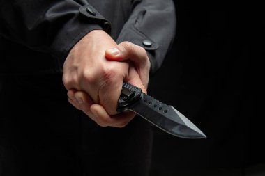 İki eli de yakın bıçak tutan bir suçlu. Siyah arka plan, silahlı saldırı konsepti..