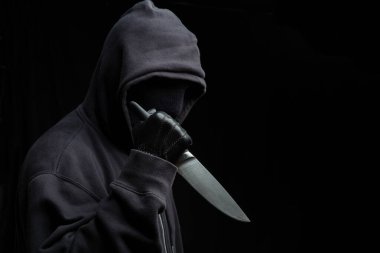 Eldivenli, siyah arka planda, silahlı saldırı konsepti olan kapüşonlu bir adam..