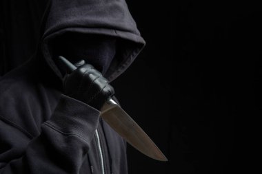 Eldivenli, siyah arka planda, silahlı saldırı konsepti olan kapüşonlu bir adam..