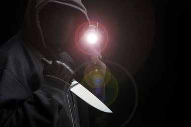 Eldivenli, siyah arka planda, silahlı saldırı konsepti olan kapüşonlu bir adam..