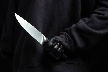 Arkasından bıçak saklayan bir hırsız, eldivenli bir silah tutan bir adam yakın çekim görüntüsü, silahlı saldırı konsepti.