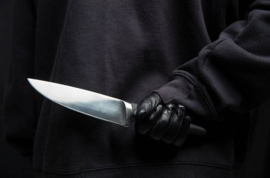 Arkasından bıçak saklayan bir hırsız, eldivenli bir silah tutan bir adam yakın çekim görüntüsü, silahlı saldırı konsepti.